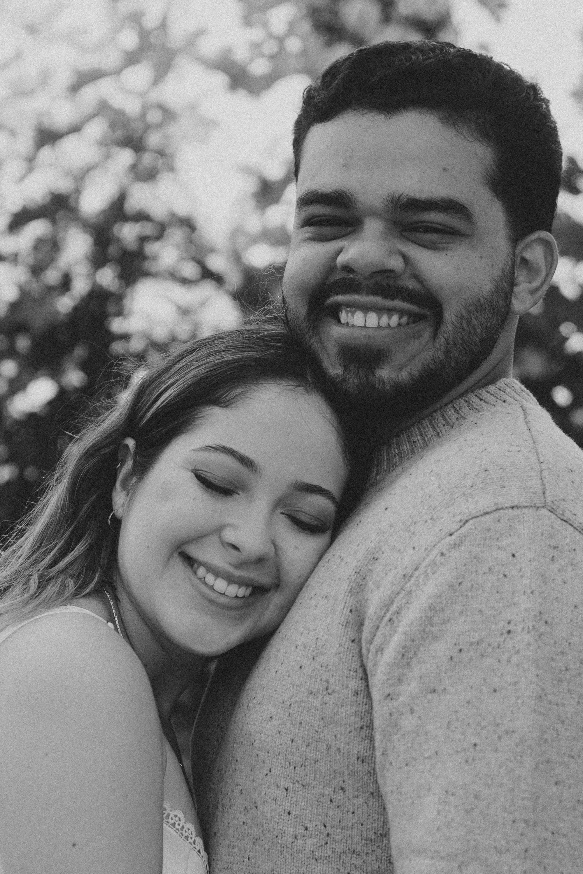 Casal abraçado sorrindo, em preto e branco