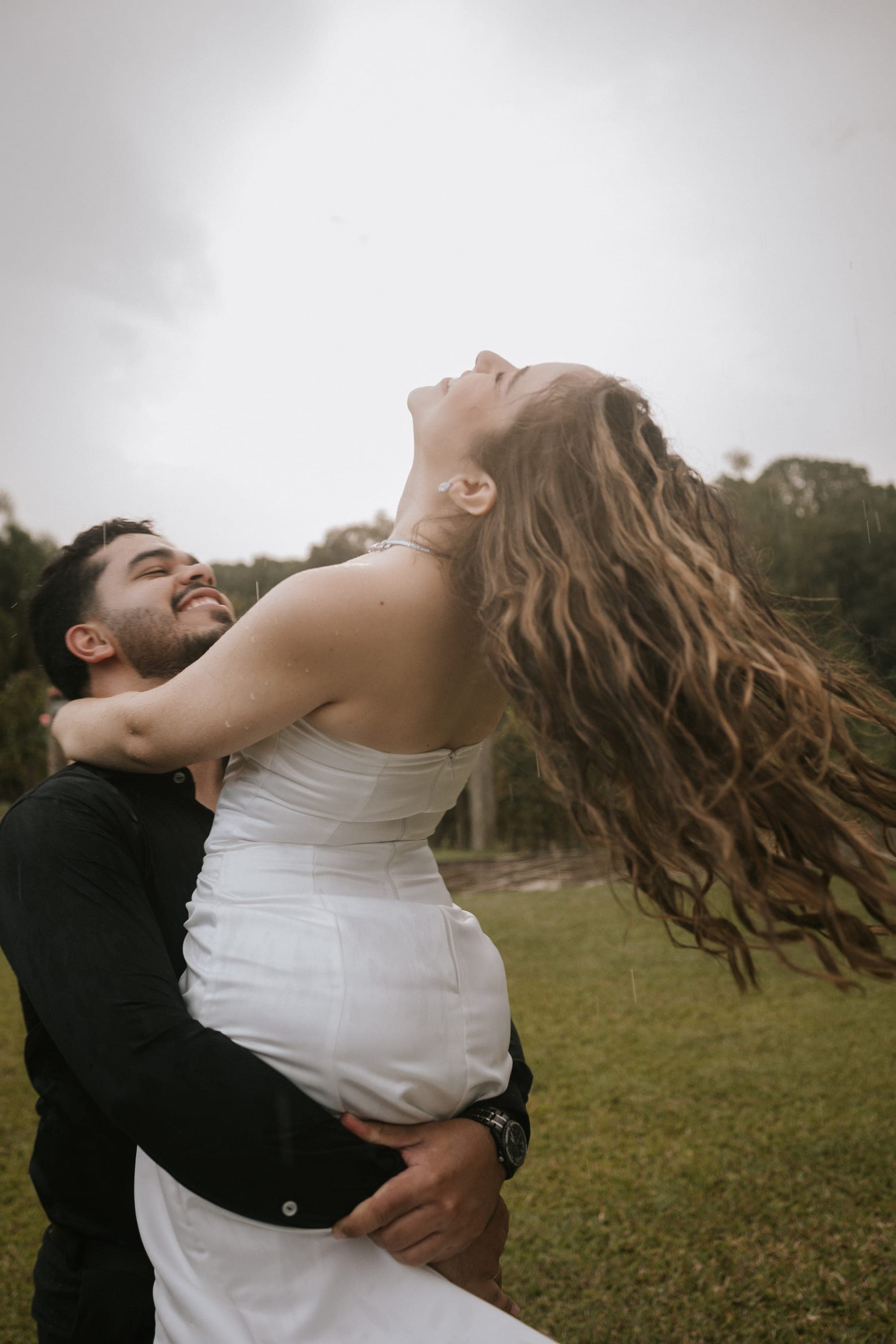 Noivo levantando a noiva, cabelo solto ao vento