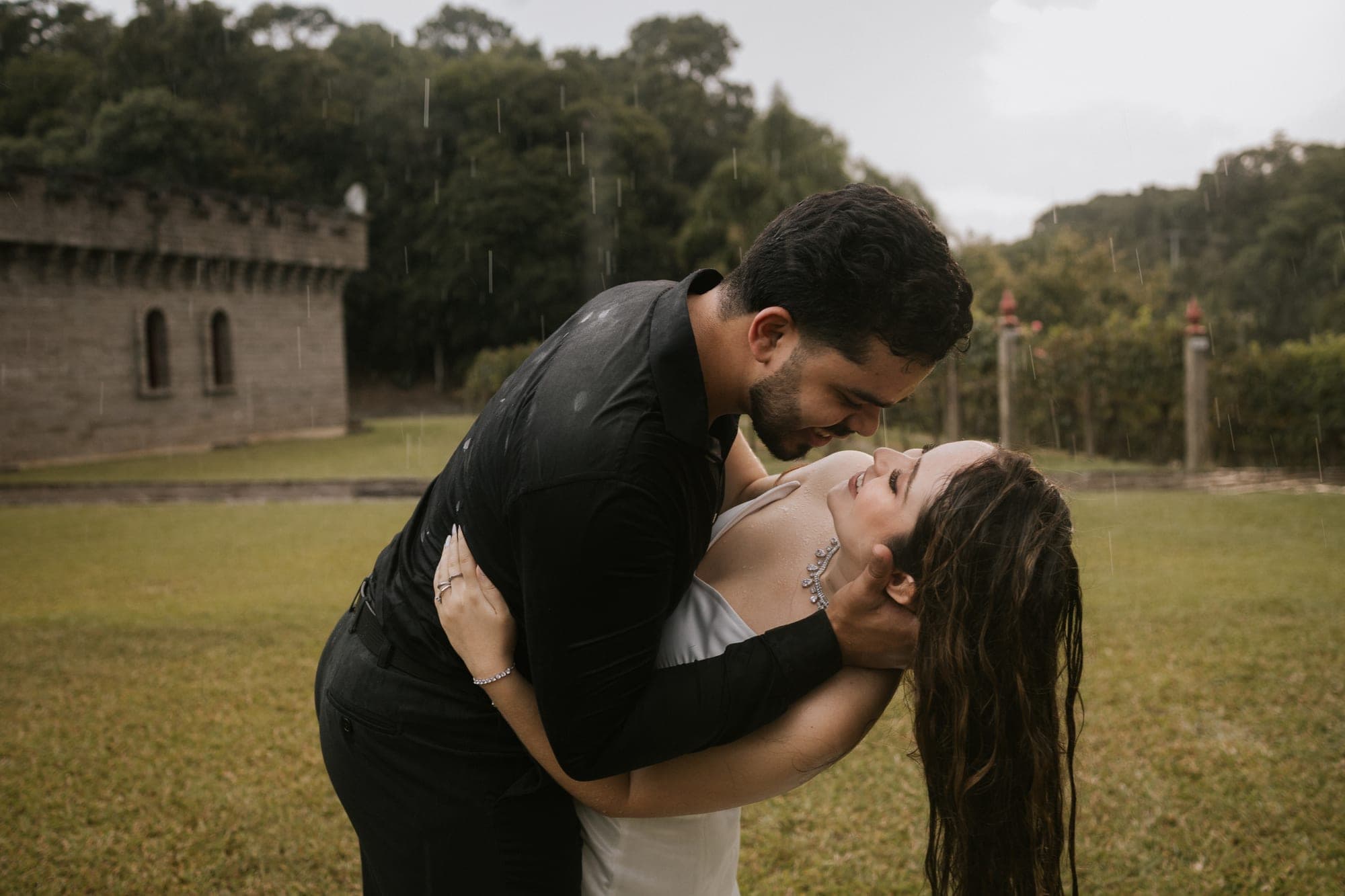 Casal se inclinando para o beijo, castelo ao fundo