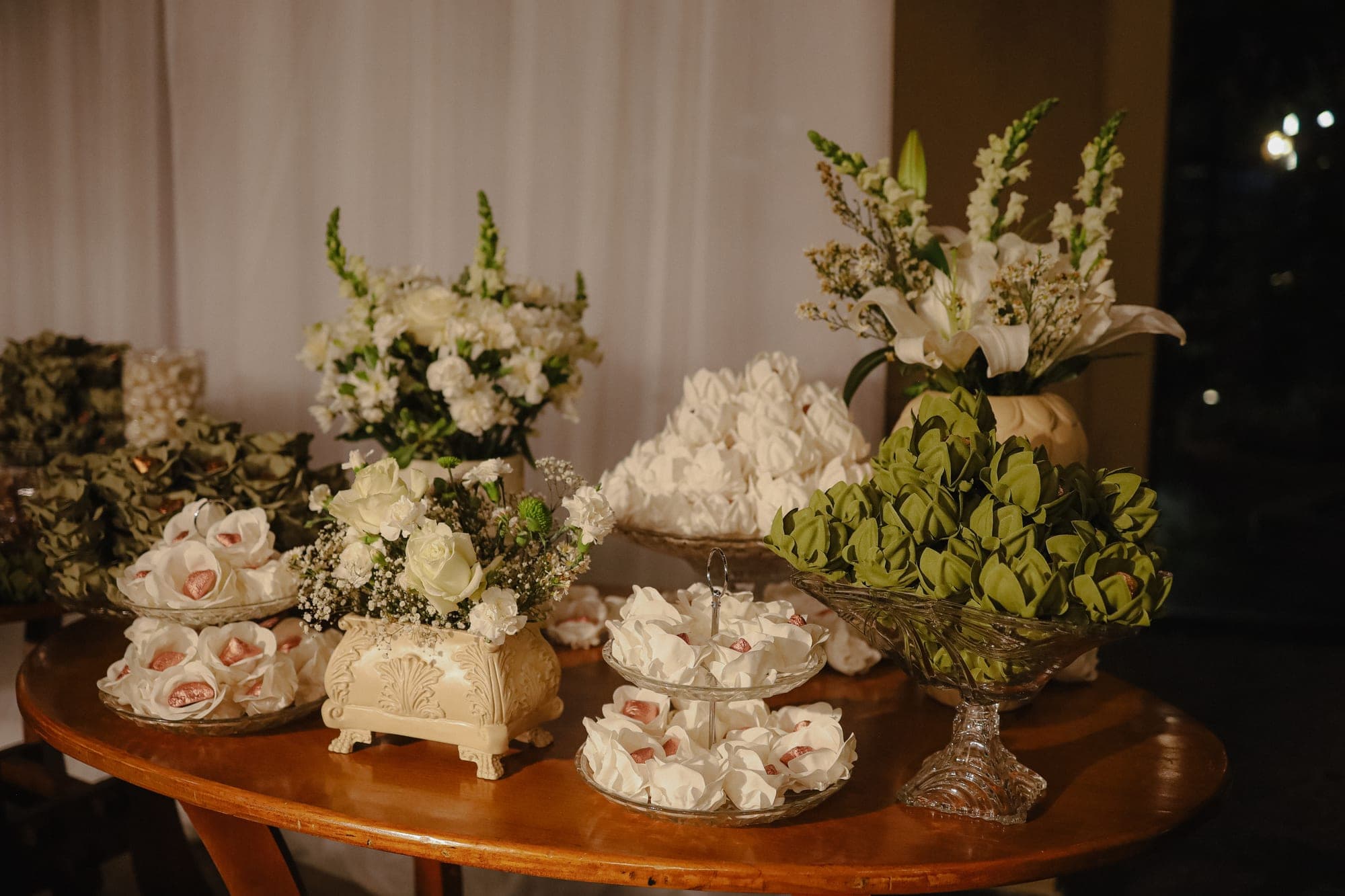 Mesa de doces montada com flores brancas